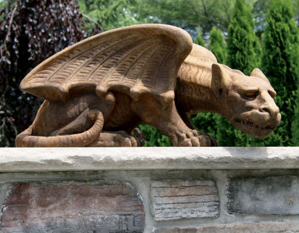 Crouching gargoyle spiny claws menacing face sculpted wings statue